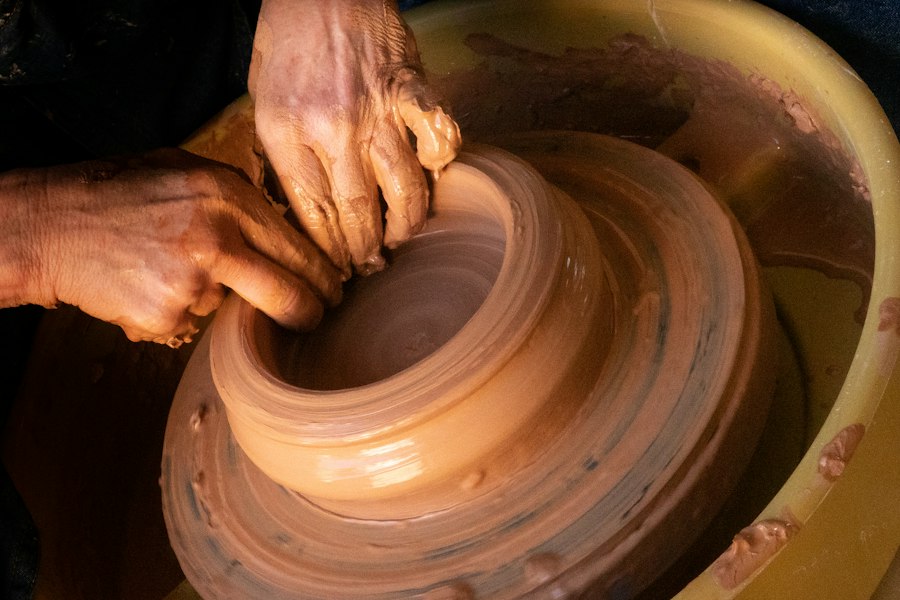Hands shaping a clay vessel
